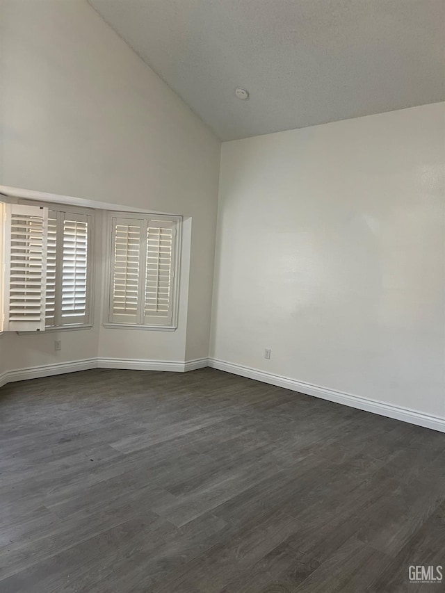 spare room with dark hardwood / wood-style flooring and vaulted ceiling