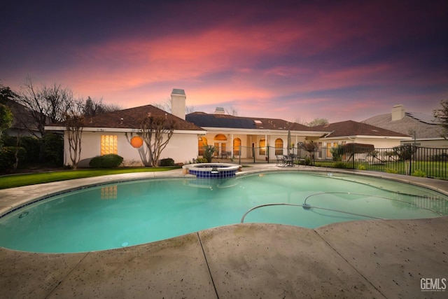 pool at dusk featuring an in ground hot tub and a patio area