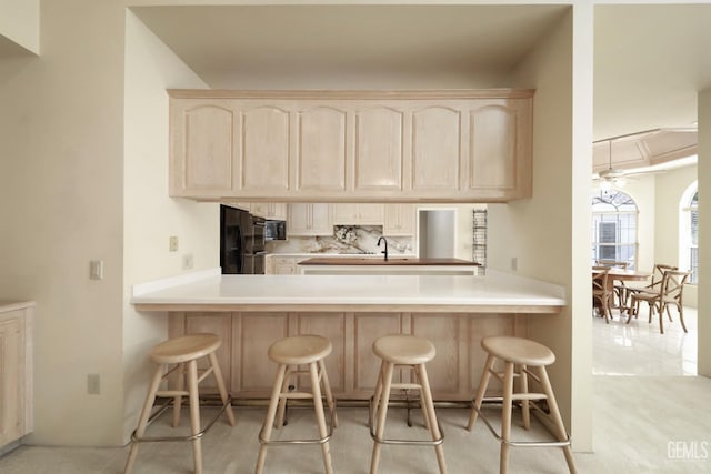 kitchen with black appliances, a breakfast bar area, and kitchen peninsula