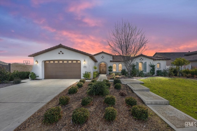 mediterranean / spanish home featuring a garage and a lawn