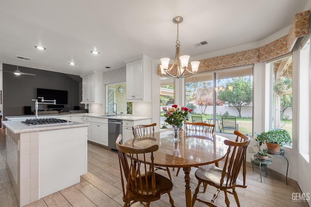 dining area featuring sink, light hardwood / wood-style flooring, and a notable chandelier