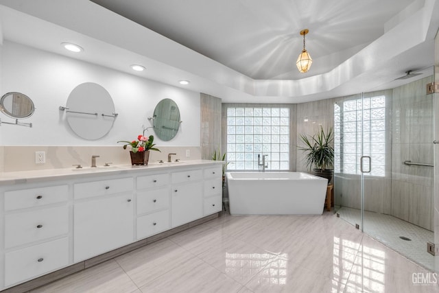 bathroom featuring vanity, plus walk in shower, and a tray ceiling