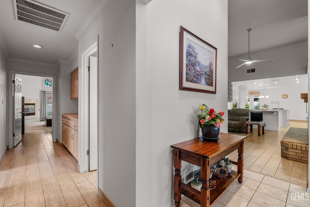 hallway with light hardwood / wood-style floors and ornamental molding