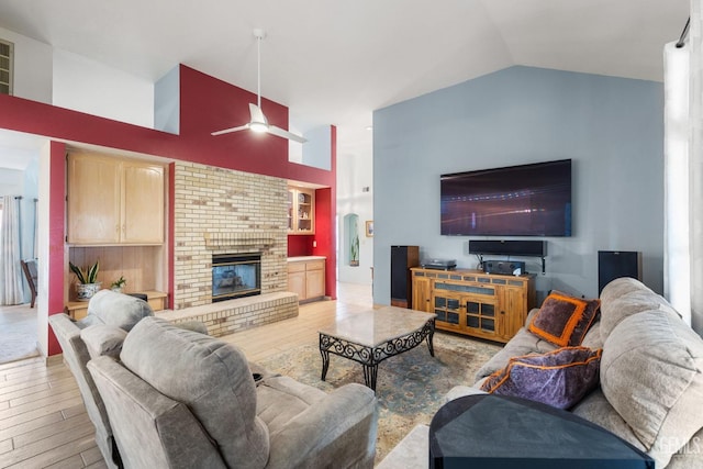 living room featuring ceiling fan, a fireplace, and vaulted ceiling