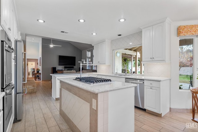 kitchen featuring ceiling fan, a center island, stainless steel appliances, kitchen peninsula, and white cabinets