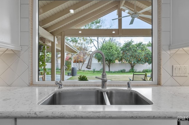 room details featuring decorative backsplash, light stone countertops, sink, and white cabinets