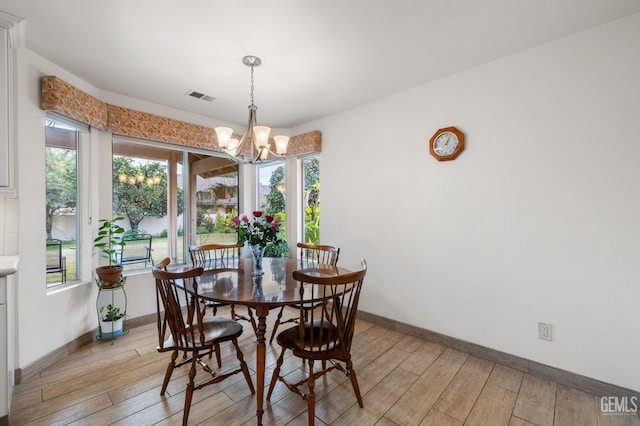 dining space with light wood-type flooring and a notable chandelier