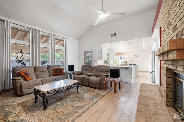 living room with ceiling fan, lofted ceiling, and a brick fireplace