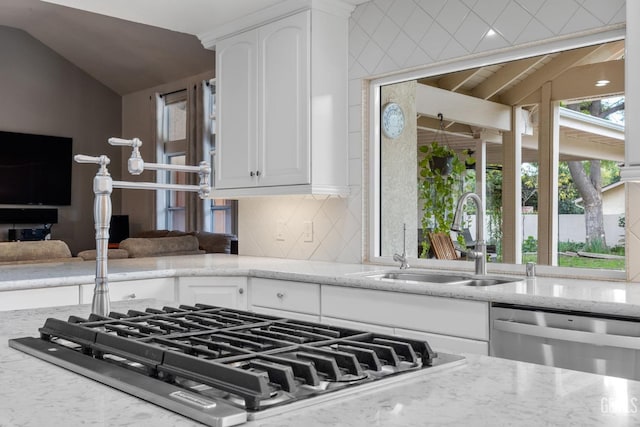 kitchen featuring light stone countertops, sink, stainless steel appliances, and vaulted ceiling