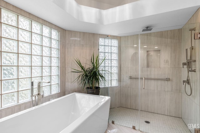 bathroom featuring tile patterned flooring, shower with separate bathtub, and tile walls