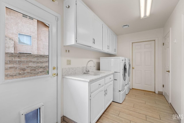 laundry area with cabinets, sink, light wood-type flooring, independent washer and dryer, and heating unit