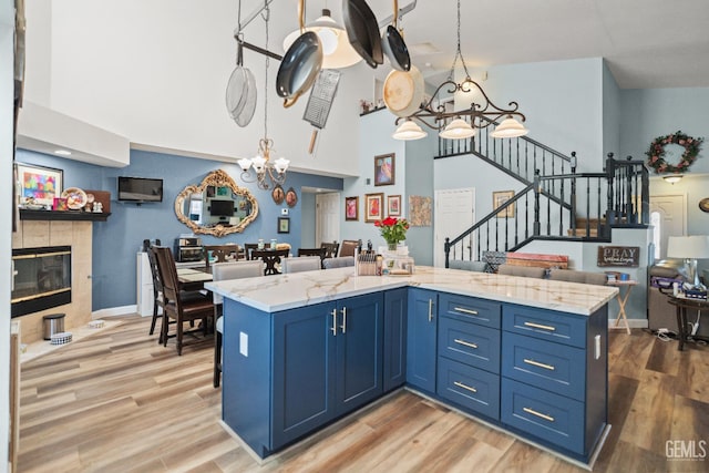 3809 Wensley Ct, Bakersfield, CA 93311 - kitchen featuring a chandelier, high vaulted ceiling, blue cabinets, and light wood-type flooring