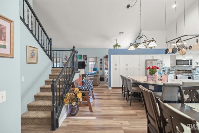 3809 Wensley Ct, Bakersfield, CA 93311 - dining room with stairs, light wood-style flooring, and high vaulted ceiling