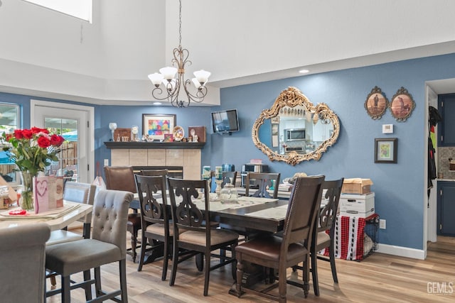 3809 Wensley Ct, Bakersfield, CA 93311 - dining area featuring wood finished floors, a chandelier, a fireplace, a high ceiling, and baseboards