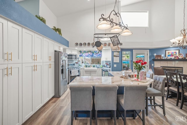 3809 Wensley Ct, Bakersfield, CA 93311 - kitchen featuring appliances with stainless steel finishes, a high ceiling, white cabinetry, a chandelier, and a sink