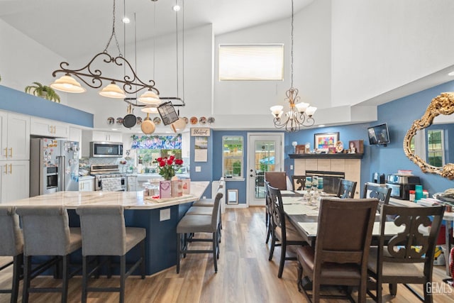 3809 Wensley Ct, Bakersfield, CA 93311 - dining space featuring a chandelier, high vaulted ceiling, light wood-style floors, and a tile fireplace