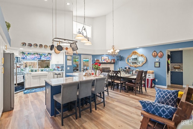 3809 Wensley Ct, Bakersfield, CA 93311 - kitchen with a high ceiling, white cabinetry, a sink, a kitchen island, and a chandelier