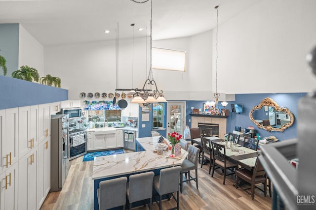 3809 Wensley Ct, Bakersfield, CA 93311 - kitchen featuring appliances with stainless steel finishes, high vaulted ceiling, a sink, a fireplace, and white cabinetry