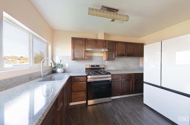 kitchen featuring sink, decorative backsplash, light stone counters, dark wood-type flooring, and stainless steel range with gas stovetop