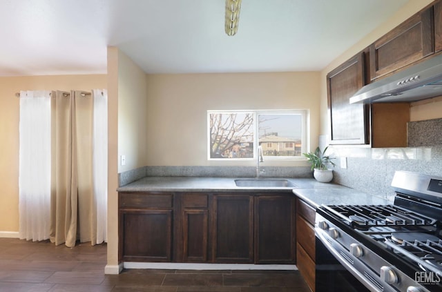 kitchen with dark wood-type flooring, sink, stainless steel gas stove, dark brown cabinets, and decorative backsplash