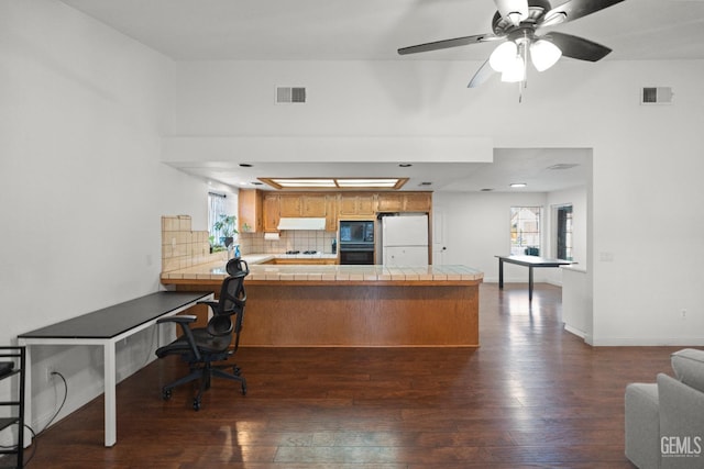 kitchen featuring backsplash, tile countertops, kitchen peninsula, and black appliances