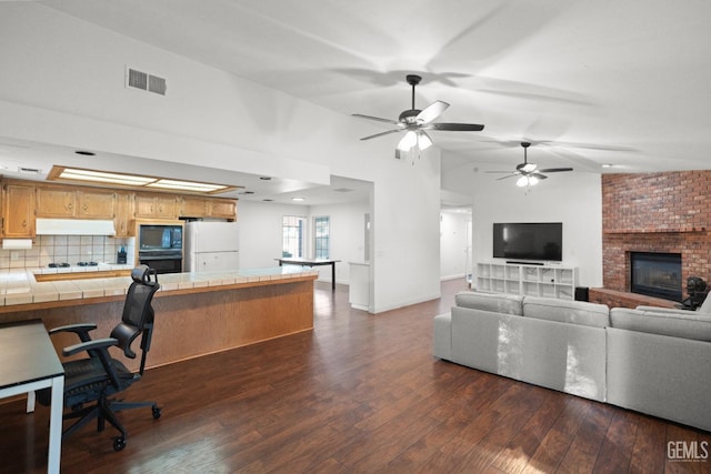 living room with dark wood-type flooring, lofted ceiling, and a fireplace