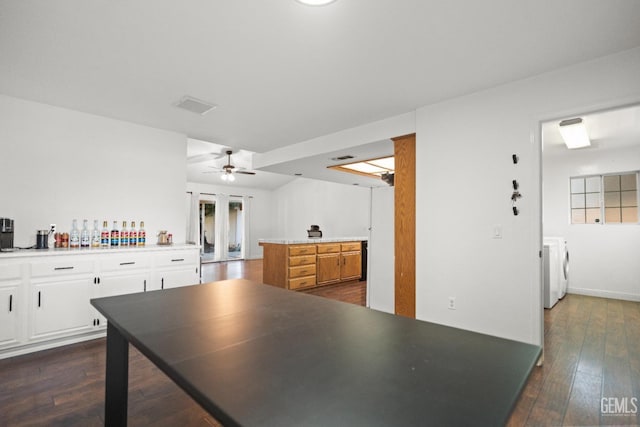 kitchen featuring ceiling fan, dark hardwood / wood-style flooring, washer and dryer, and white cabinets