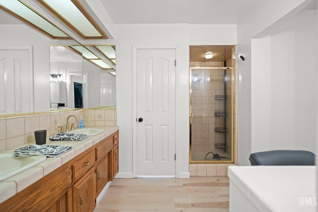 bathroom featuring hardwood / wood-style flooring, vanity, an enclosed shower, and backsplash