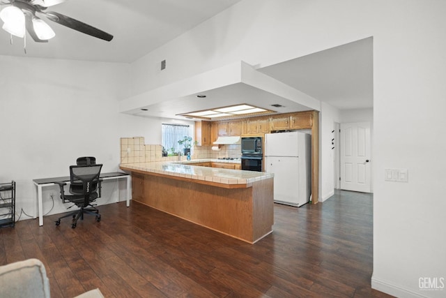 kitchen featuring decorative backsplash, dark wood-type flooring, black appliances, and kitchen peninsula