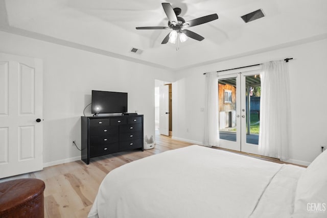 bedroom with french doors, access to outside, a tray ceiling, ceiling fan, and light hardwood / wood-style floors