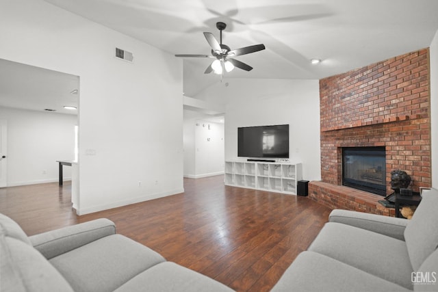 living room with hardwood / wood-style flooring, ceiling fan, vaulted ceiling, and a brick fireplace