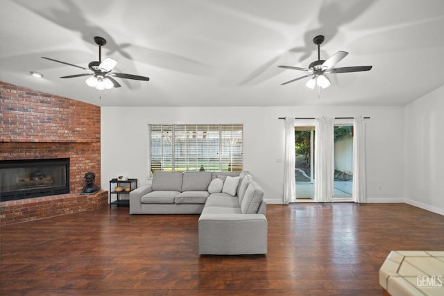 living room with vaulted ceiling, a brick fireplace, dark hardwood / wood-style floors, and ceiling fan