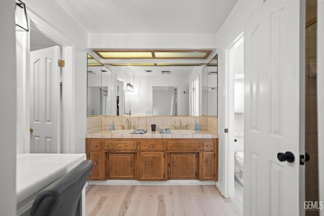 bathroom featuring vanity, backsplash, wood-type flooring, and toilet