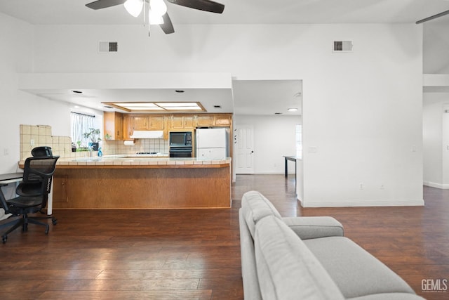 living room featuring dark wood-type flooring, ceiling fan, and a tray ceiling