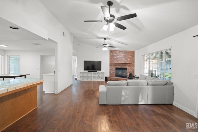 unfurnished living room with ceiling fan, lofted ceiling, dark hardwood / wood-style floors, and a brick fireplace