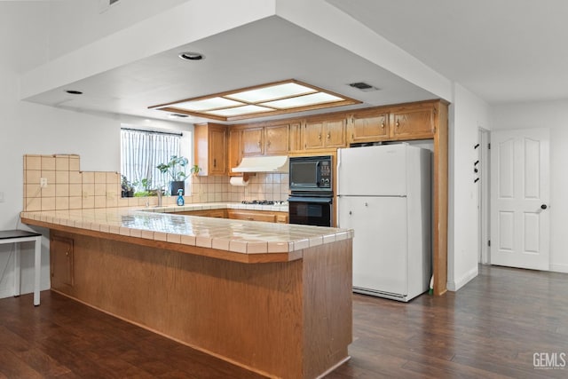 kitchen featuring tile countertops, kitchen peninsula, decorative backsplash, and black appliances