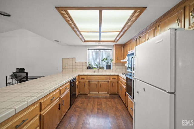 kitchen with dark hardwood / wood-style floors, tasteful backsplash, sink, tile counters, and black appliances