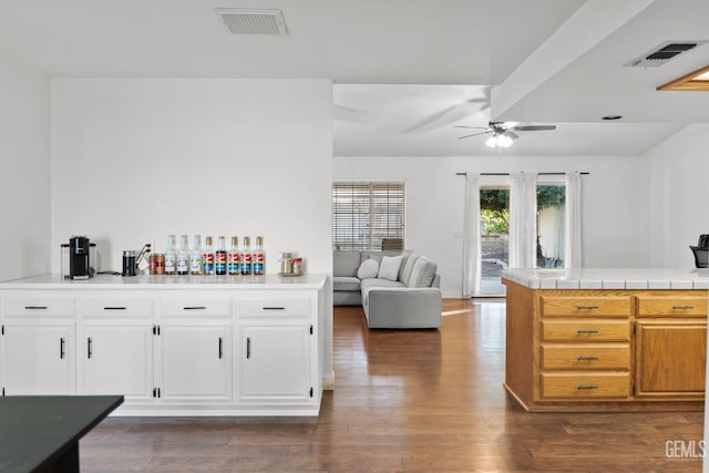 kitchen featuring white cabinetry, dark hardwood / wood-style floors, tile countertops, and kitchen peninsula