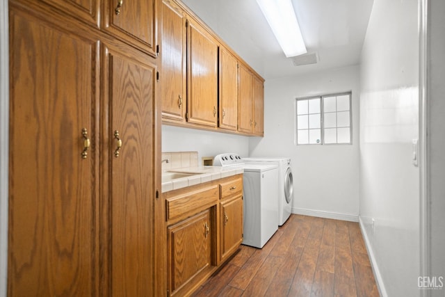 laundry area with cabinets, dark hardwood / wood-style floors, washer and clothes dryer, and sink