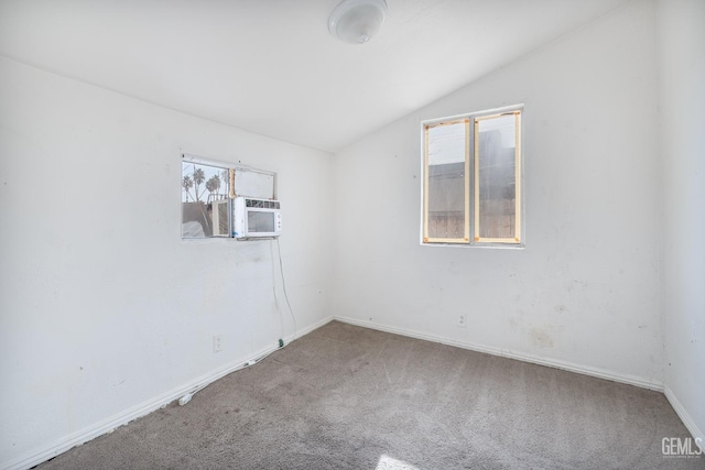 carpeted spare room featuring cooling unit and vaulted ceiling