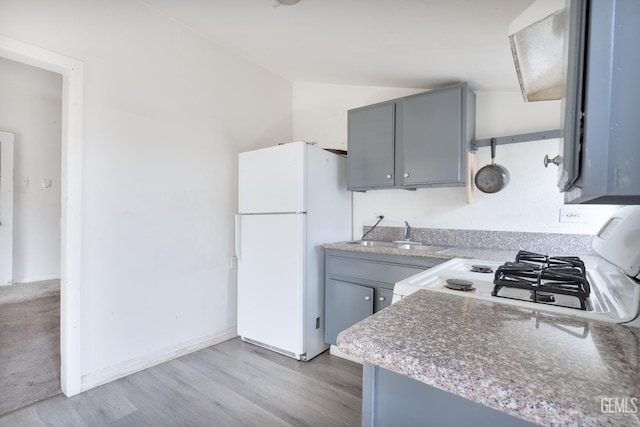 kitchen featuring light hardwood / wood-style floors, sink, gray cabinets, white fridge, and range with gas stovetop