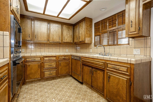 kitchen featuring dishwasher, sink, tile countertops, and backsplash