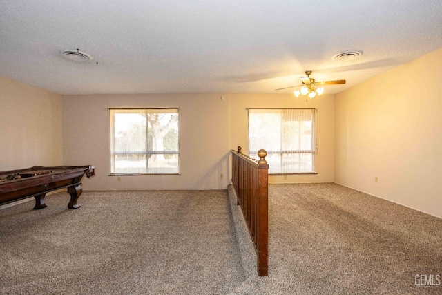 recreation room with ceiling fan, plenty of natural light, carpet flooring, and a textured ceiling