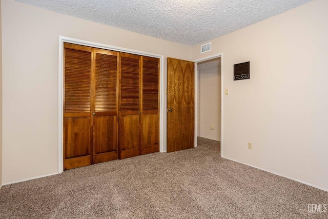 unfurnished bedroom featuring carpet floors, a textured ceiling, and a closet