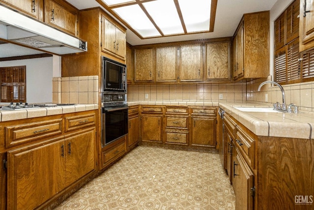 kitchen featuring sink, backsplash, tile counters, and black appliances