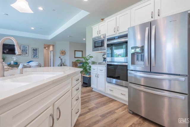 13620 Stonethwaite Ln, Bakersfield, CA 93311 - kitchen featuring appliances with stainless steel finishes, light wood-style floors, white cabinets, a skylight, and recessed lighting