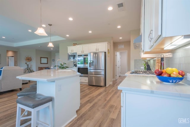 13620 Stonethwaite Ln, Bakersfield, CA 93311 - kitchen with appliances with stainless steel finishes, decorative backsplash, white cabinets, open floor plan, and light wood-style floors