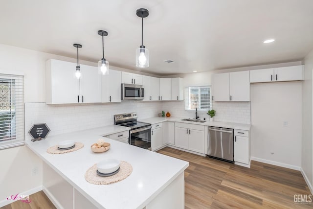 kitchen with kitchen peninsula, white cabinetry, hanging light fixtures, and stainless steel appliances