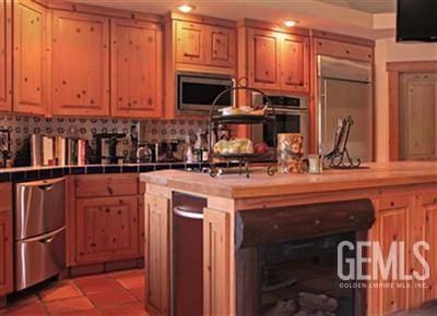 kitchen featuring appliances with stainless steel finishes, a center island with sink, and tile countertops