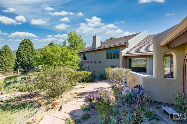 28221 Cumberland Rd, Tehachapi, CA 93561 - view of home's exterior with stucco siding, a chimney, a tiled roof, and a patio area